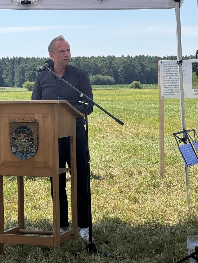 Umweltminister Thorsten Glauber steht am Rednerpult und hält eine Rede zum festlichen Anlass, der Landschaftspflegeverbands Kelheim VöF e.V. ist der erste Landschaftspflegeverband  in Bayern gewesen.