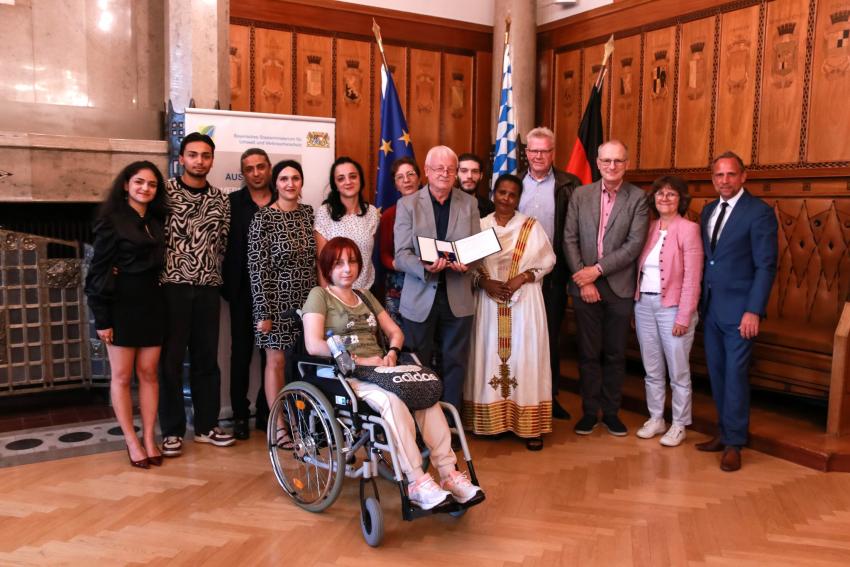 Gruppenfoto zeigt Umweltminister Thorsten Glauber (re) zusammen mit dem neuen Ordensträger Günther Hinterobermeier (er hält die Verleihungsurkunde mit dem  Bundesverdienstkreuz in die Kamera) und weiteren geladenen Gästen. ©Foto Benjamin Böhm