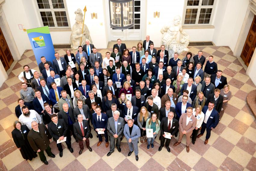 Das Gruppenfoto zeigt Bayerns Umweltminister Thorsten Glauber mit den Teilnehmern des Umwelt- und Klimapakts 2023 im Schloss Nymphenburg (Hubertussaal)