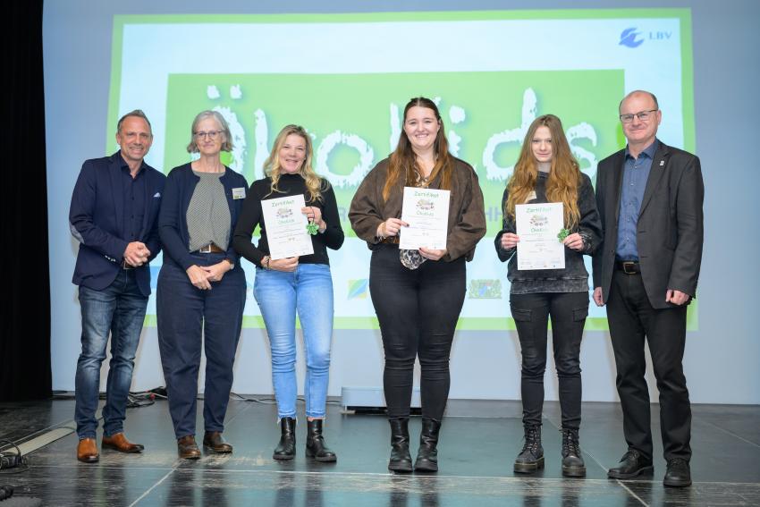 Umweltminister Thorsten Glauber (l.) und Norbert Schäffer, Vorsitzender des Landesbund für Vogelschutz in Bayern e.V. (r.) überreichen die Auszeichnungsurkunden ÖkoKids an die Kitas, von links: Kath. Kindertagesstätte St. Michael Marktgraitz, Kinderwelt Gerhardshofen und Kindertagesstätte Regenbogen Oberreichenbach. Carmen Günnewig v. LBV unterstützt als Projektleitung das Projekt ÖkoKids (2. v. l.).