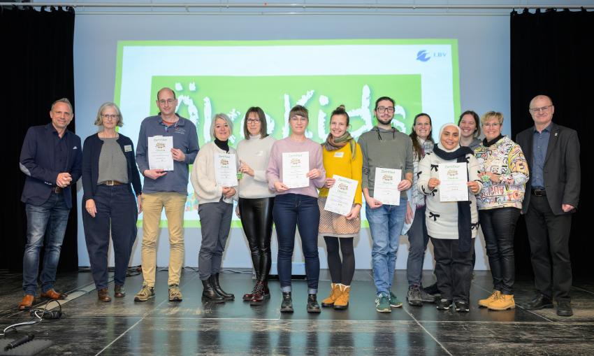 Umweltminister Thorsten Glauber (l.) und Norbert Schäffer, Vorsitzender des Landesbund für Vogelschutz in Bayern e.V. (r.) überreichen die Auszeichnungsurkunden ÖkoKids an die Kitas, von links: Städtische Kindertagesstätte Neunhof Lauf/Pegnitz, Ev. Kinderhaus Regenbogen Ottensoos, Ev. Hort Burgthann, Evangelischer Kindergarten Eismannsberg Wind-, Wald- & Wurzelkinder, Haus für Kinder Familienzentrum Reutersbrunnen Nürnberg und Ev. Kindertagesstätte Falkenheim. Carmen Günnewig v. LBV unterstützt als Projektleitung das Projekt ÖkoKids (2. v. l.).