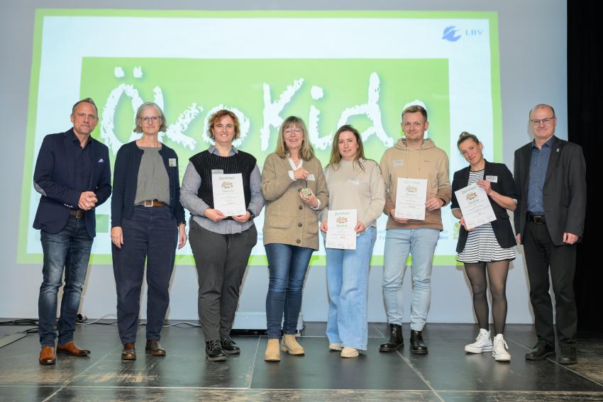 Umweltminister Thorsten Glauber (l.) und Norbert Schäffer, Vorsitzender des Landesbund für Vogelschutz in Bayern e.V. (r.) überreichen die Auszeichnungsurkunden ÖkoKids an die Kitas, von links: AWO Schülerhort Weltentdecker Coburg, Kinderhaus St. Josef Unterleinleitner, Kinderhaus der Stadt Coburg und Kindertagesstätte St. Josef Gaustadt. Carmen Günnewig v. LBV unterstützt als Projektleitung das Projekt ÖkoKids (2. v. l.).