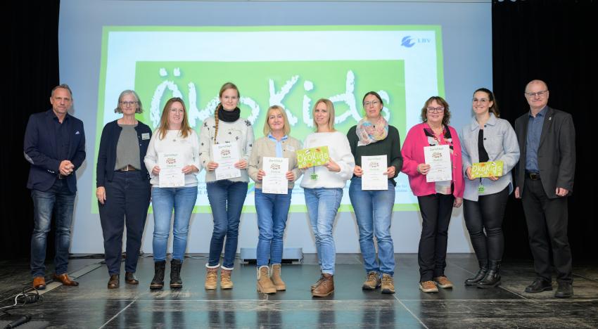 Umweltminister Thorsten Glauber (l.) und Norbert Schäffer, Vorsitzender des Landesbund für Vogelschutz in Bayern e.V. (r.) überreichen die Auszeichnungsurkunden ÖkoKids an die Kitas, von links: Kindergarten Zell a.E., Naturkindergarten am Wendelberg in Bessenbach, Kindergarten Rappelkiste Rimpar, Kita Regenbogenhaus Zeil, Kita Euerdorf Paradieso. Carmen Günnewig v. LBV unterstützt als Projektleitung das Projekt ÖkoKids (2. v. l.).