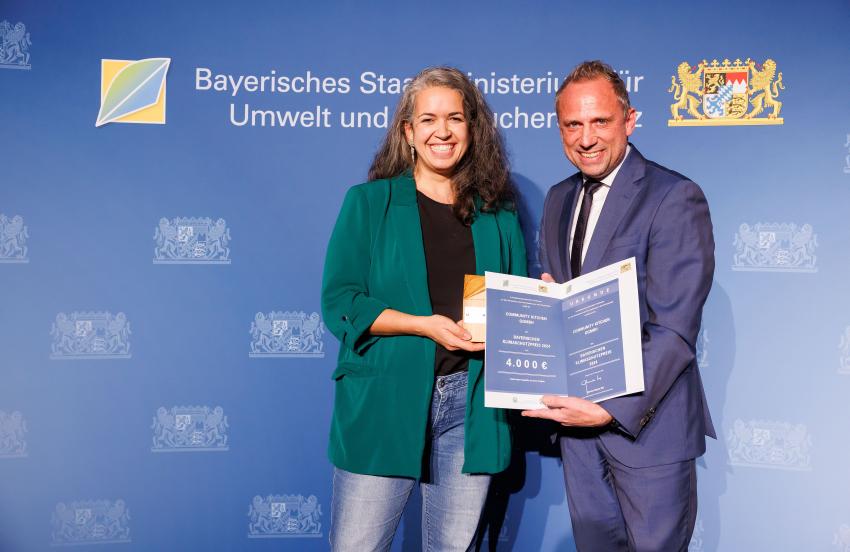 Die Preisträgerin und Umweltminister Thorsten Glauber zeigen zusammen den Klimaschutzpreis und die Urkunde.