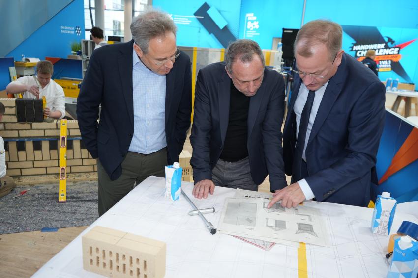 Umweltminister Thorsten Glauber besucht den Stand des Deutschen Baugewerbe und schaut sich die Baupläne an