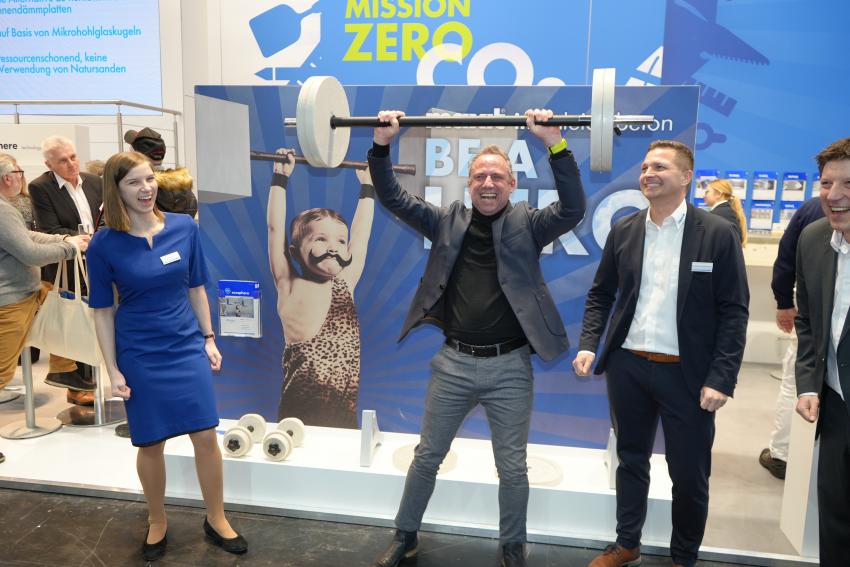 Umweltminister Thorsten Glauber hebt die Leichtbeton-Langhantel am Messestand der Maxit-Gruppe