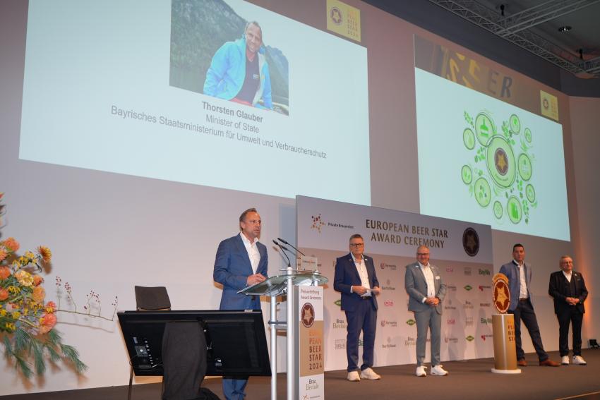 Umweltminister Thorsten Glauber nimmt an der diesjährigen BrauBeviale 2024 und Preisverleihung European Beer Star und European Beer Star Future Award im Nürnberger Convention Center (NCC) teil. Das Foto zeigt von links nach rechts: Umweltminister Thorsten Glauber (steht am Redepult und hält eine Rede), Stefan Stang (Geschäftsführer Private Brauereien Bayern und Deutschland), Georg Rittmayer und Martin Schimpf (Präsidenten der Privaten Brauereien Deutschland), Roland Demleitner (Geschäftsführer von Private Brauereien Bayern und Deutschland). 
