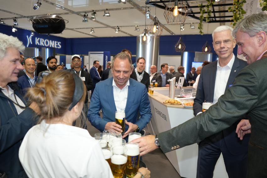 Umweltminister Thorsten Glauber übernimmt ein Glas Bier am Stand der Krones AG.
