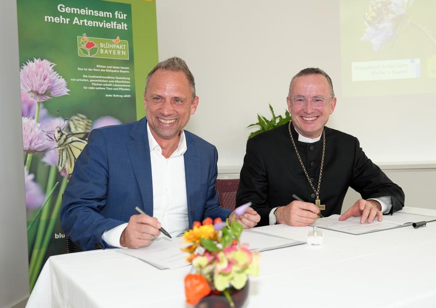 Beim Festakt zur Erneuerung der Blühpakt-Allianz am 06.11.2024 unterzeichnen Staatsminister Thorsten Glauber und Landesbischof Christian Kopp die neue Allianz-Vereinbarung.