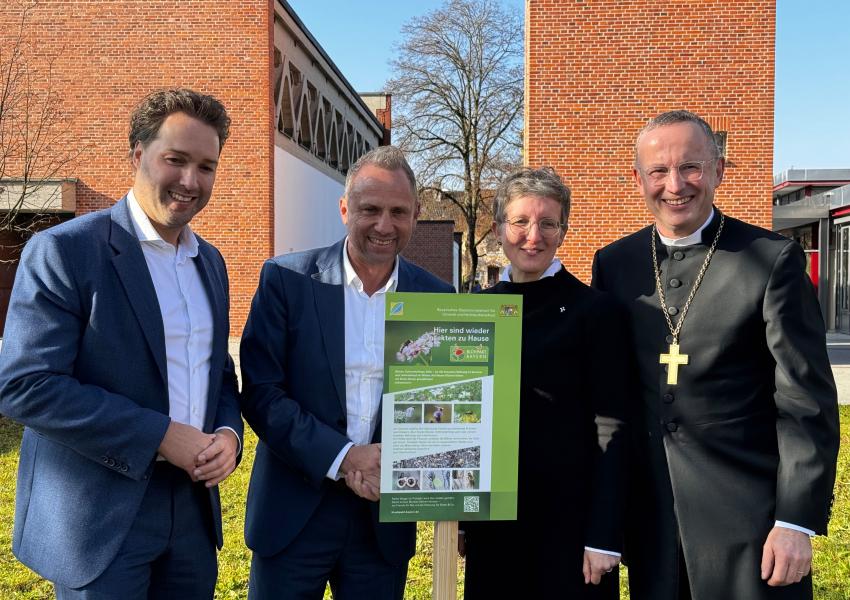 Bürgermeister Dr. Andreas Bukowski, Staatsminister Thorsten Glauber, Pfarrerin Annedore Becker und Landesbischof Christian Kopp freuen sich über das neu aufgestellte Blühpakt-Schild. 