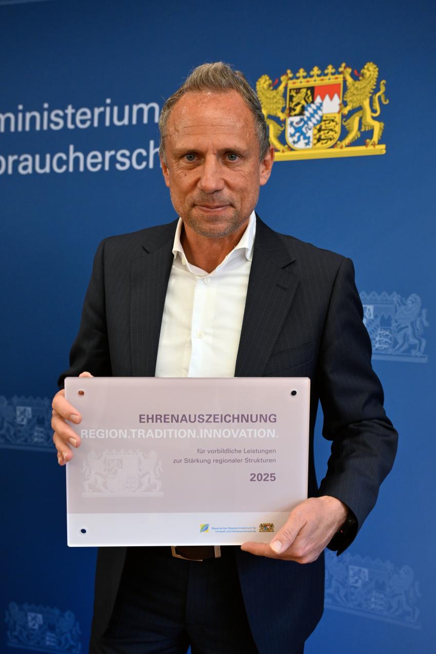 Umweltminister Thorsten Glauber hält die Ehrenauszeichnung REGION.TRADITION.INNOVATION in der Hand