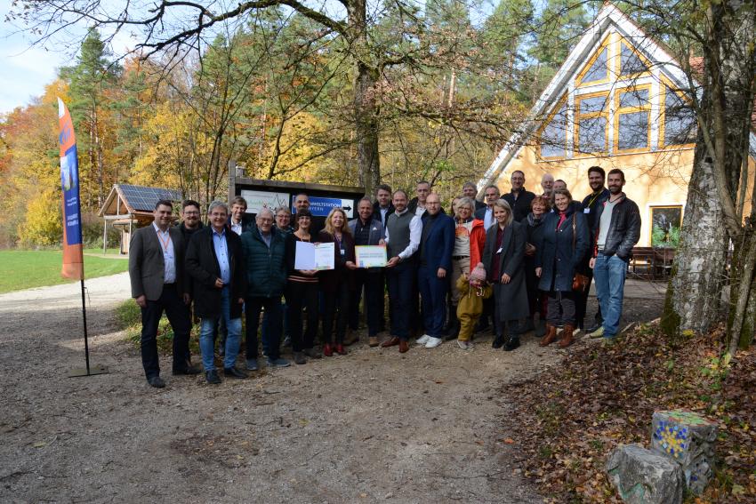 Gruppenfoto vor dem Jugendhaus, Umweltminister Thorsten Glauber überreicht feierlich das Anerkennungsschild und die Anerkennungsurkunde an die staatlich anerkannte Umweltstation Lern- und Erfahrungsraum Edelweißhütte.