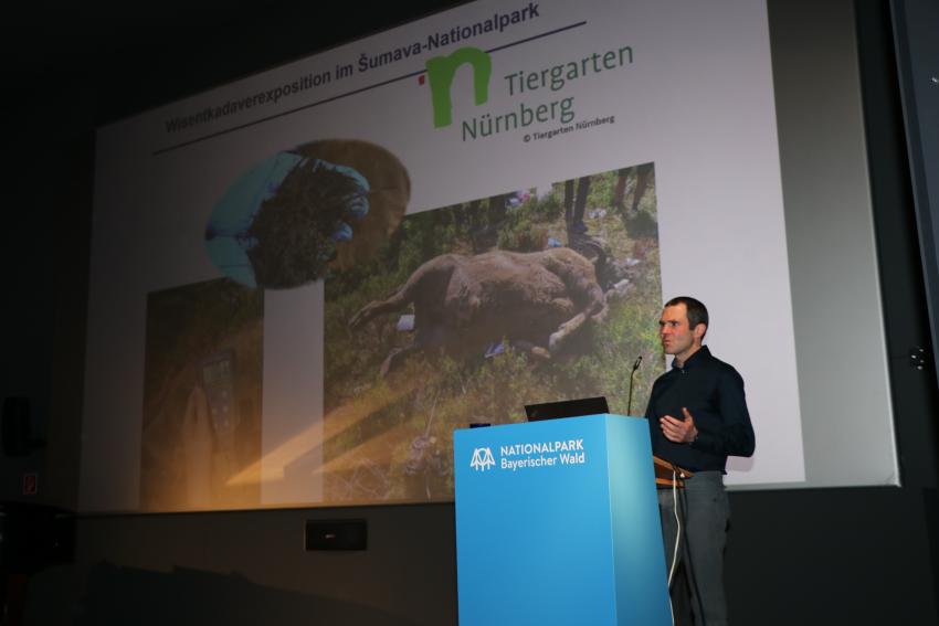 Am Rednerpult steht Herr Dr. Christian von Hoermann von und zu Guttenberg und hält einen Vortrag zu seiner Forschungsarbeit mit Schwerpunkt Kadaver im Ökosystem. 