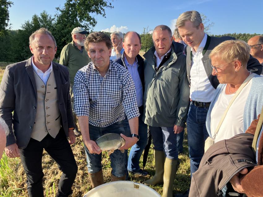 Das Gruppenfoto zeigt u. a. Umweltminister Thorsten Glauber (li.) und Dr. Thomas Speierl (Bezirk Oberfranken/Fachberatung für Fischerei) hält einen Teichkarpfen in den Händen.