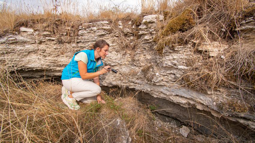 Naturtalent Chiara Engelbrecht untersucht in der Hocke mit einer Taschenlampe eine Höhle im moosbewachsenen Gipshügel.