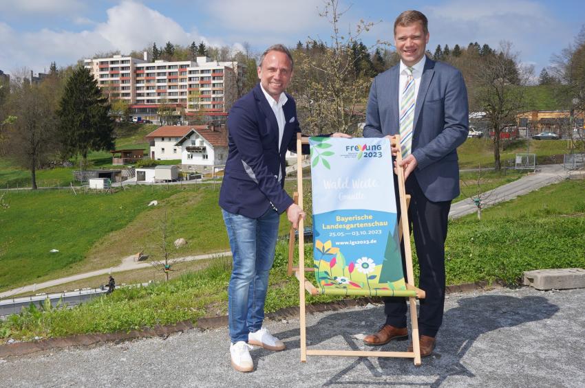 Umweltminister Thorsten Glauber und Freyungs Bürgermeister Dr. Olaf Heinrich präsentieren einen Liegestuhl mit dem Logo der Landesgartenschau 2023