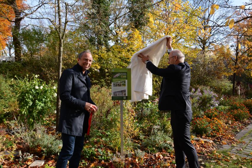 Umweltminister Thorsten Glauber und Enno Weidt, Dekan und Pfarrer in St. Johannis, enthüllen das Schild für die Ausweisung der Blühpakt-Fläche.