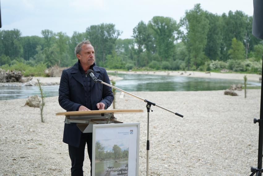 Umweltminister Thorsten Glauber steht am Isarufer und hält eine Rede zur Einweihung der fertiggestellten Renaturierungsmaßnahme der Isar am Angergries in Plattling.