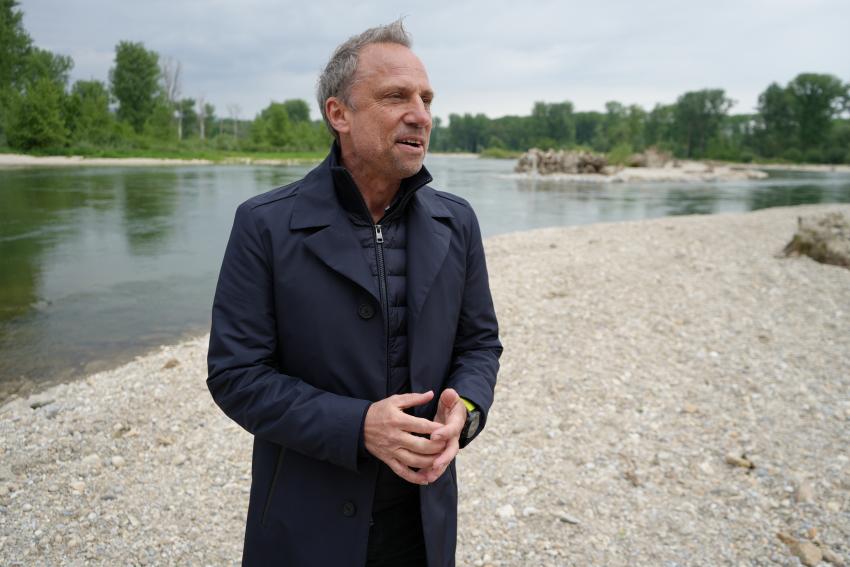 Umweltminister Thorsten Glauber steht am Ufer der Isar
