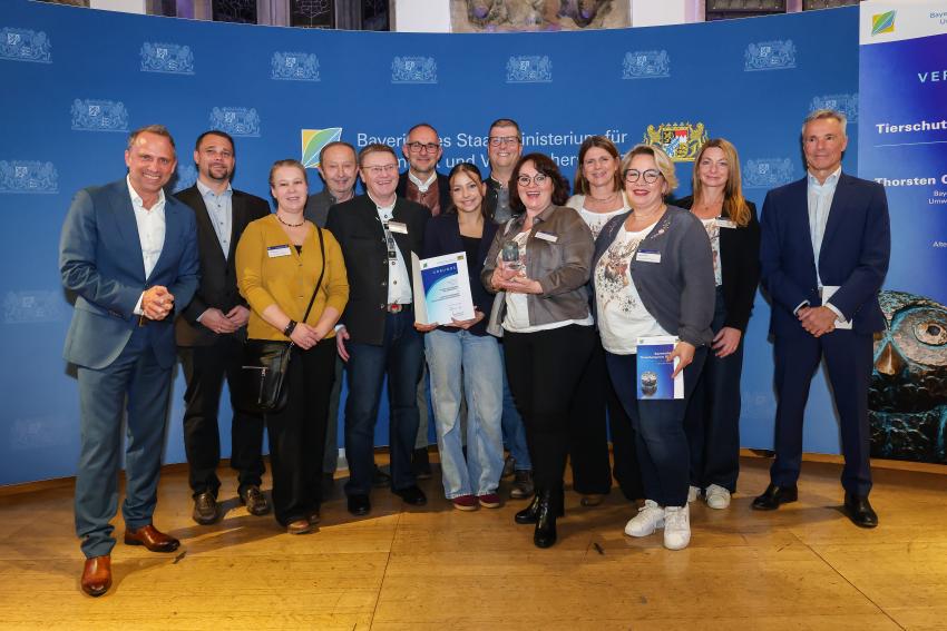 Das Foto zeigt den Bayerischen Umweltminister Thorsten Glauber und Hannes Jaenicke zusammen mit den Tierschutzpreisträgerinnen und Preisträgern des Kitzrettung Pinzberg und Umgebung e. V.