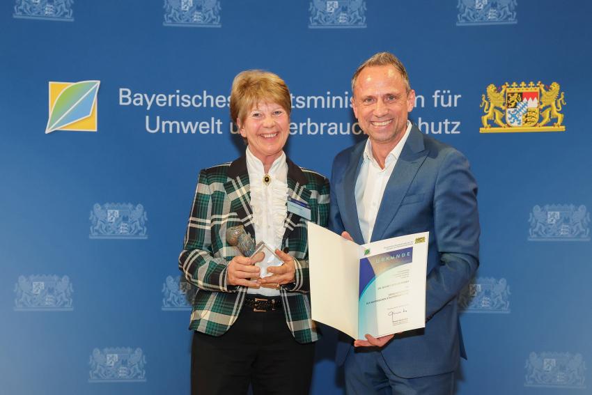 Das Foto zeigt den Bayerischen Umweltminister Thorsten Glauber mit den Tierschutzpreisträgerin Dr. Margit Zeitler-Feicht, die Auszeichnungsurkunde und den Tierschutzpreis.