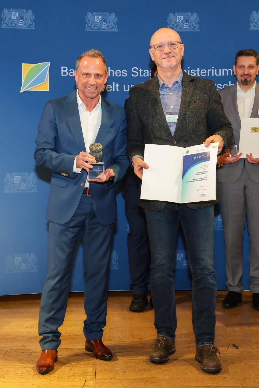 Das Foto zeigt den Bayerischen Umweltminister Thorsten Glauber mit einem Vertreter der Wildtier-Rettung Pfaffenwinkel e. V., die Auszeichnungsurkunde und den Tierschutzpreis.