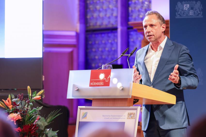 Umweltminister Thorsten Glauber steht am Rednerpult und hält eine Festansprache.