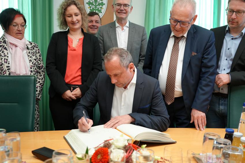 Umweltminister Thorsten Glauber schreibt in das Gästebuch der Stadt Aichach.