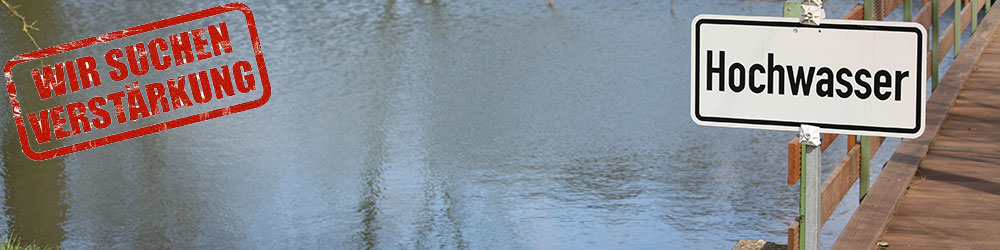 Das Bild zeigt einen Fluss mit dem Schild Hochwasser
