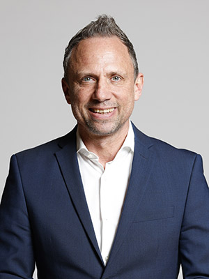 Portrait des Umweltministers Thorsten Glauber im Anzug vor grauem Hintergrund