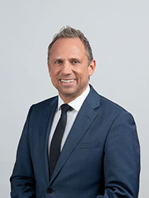 Portrait des Umweltministers Thorsten Glauber im Anzug vor grauem Hintergrund