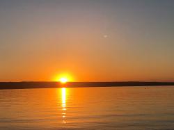 Blick vom Osten her über den Ammersee zum anderen Ufer, wo die Abendsonne  noch halb am Horizont steht und das Wasser golden schimmern lässt.