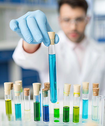 Das Bild zeigt einen Mann im Labor der ein Reagenzglas aus einem Ständer nimmt