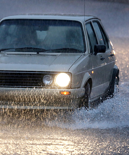 Das Bild zeigt ein Auto, das durch Hochwasser fährt