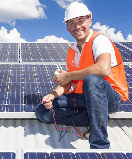 Das Bild zeigt einen Mann auf einem Dach, der eine Photovoltaikanlage installiert